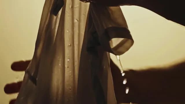 Close-up of Hands Wringing Wet White Shirt with Dripping Water