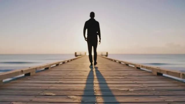 Silhouette of Man Walking on Pier at Sunrise