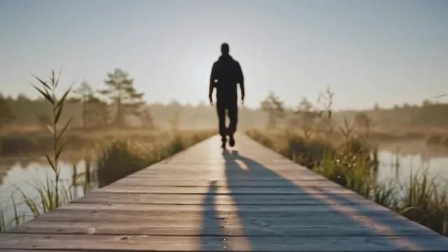Silhouette Walking on Boardwalk in Misty Marsh at Sunrise