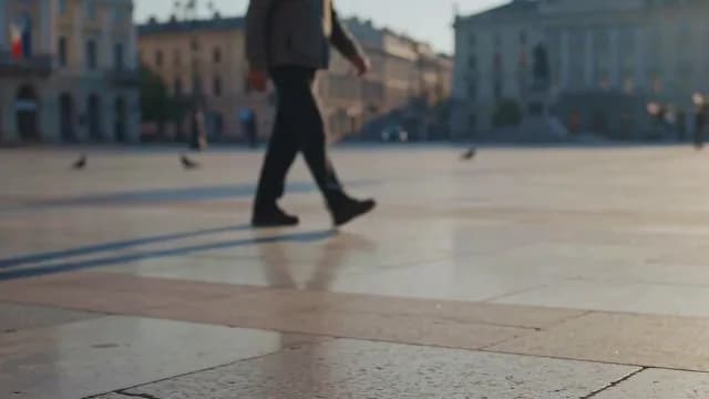 Blurred Man Walking Across Sunlit European City Square at Golden Hour