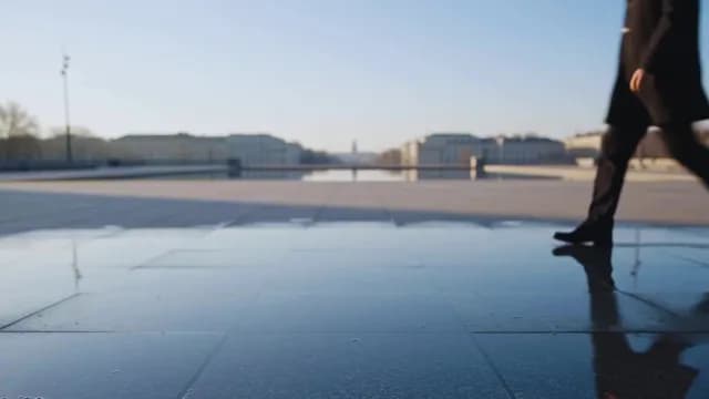 Businessman Walking Across Reflective Urban Plaza