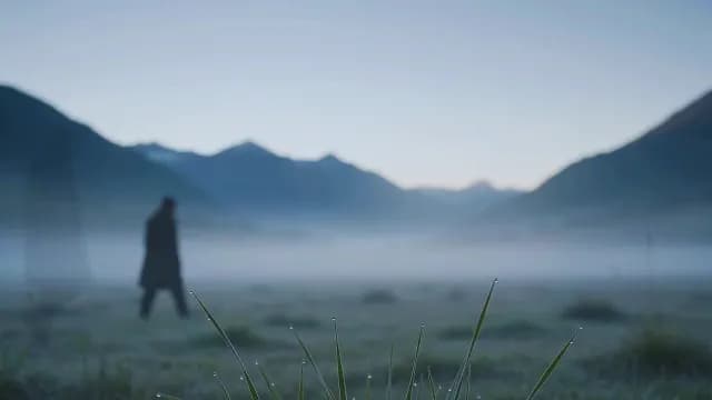 Lone Figure Walking Through Foggy Mountain Valley at Dawn