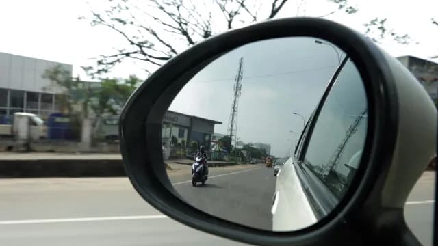 Car Side Mirror Reflection of Traffic and Scooter on Highway
