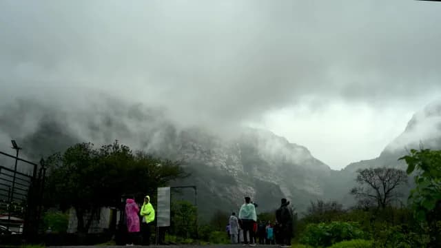 Tourists in Raincoats Watching Foggy Mountains During Monsoon