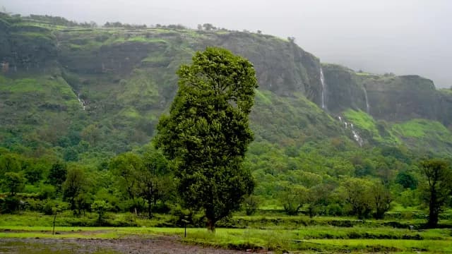 Lush Green Mountain Landscape with Cascading Waterfalls and Mist