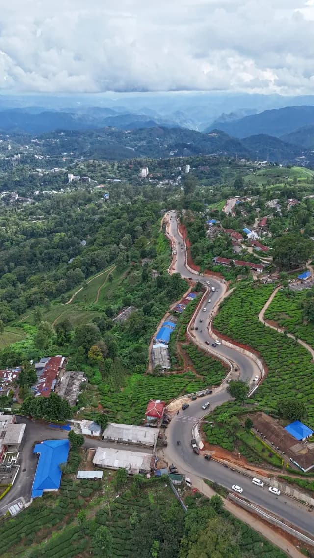 Winding Mountain Road Through Tea Plantations and Village Aerial View Munnar Kerala