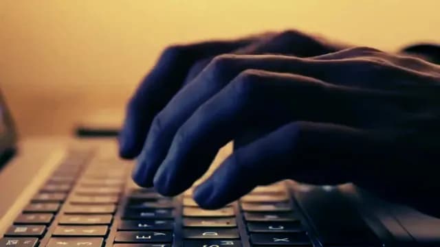 Close-Up of Hands Typing on Laptop Keyboard in Low Light