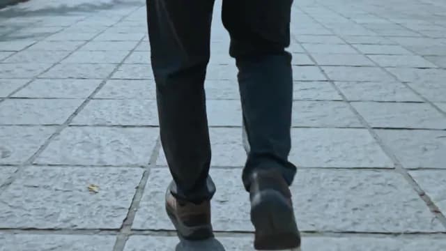 Low Angle View of Man Walking on Stone Paved Sidewalk