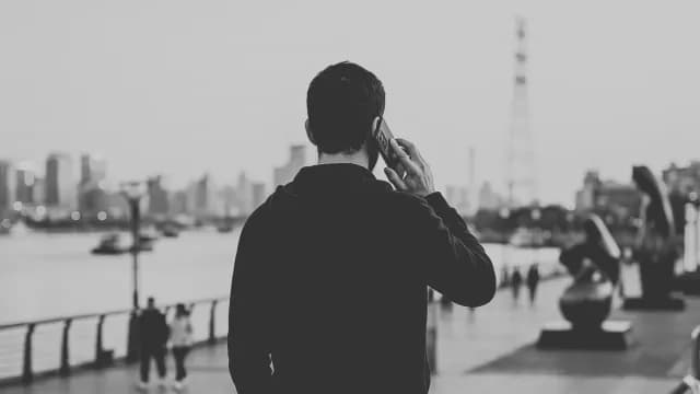 Man Talking on Smartphone by Urban Waterfront in Black and White