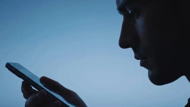 Man Using Smartphone in Dark Profile View