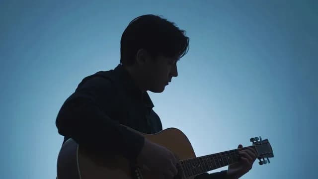 Silhouette of Man Playing Acoustic Guitar Against Blue Background
