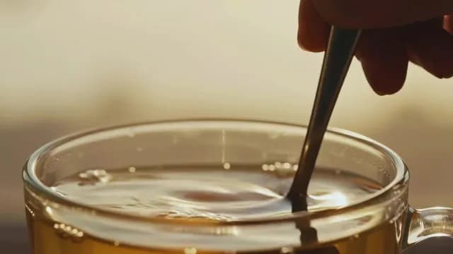 Stirring hot tea in golden morning light