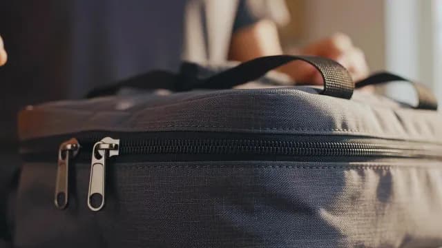 Close-up of Person Closing Grey Zippered Travel Bag