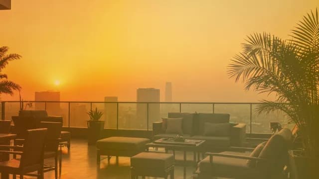Golden Sunset Over Modern Rooftop Lounge and Urban City Skyline