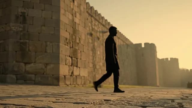 Man Silhouette Walking Past Ancient Fort Wall at Sunset