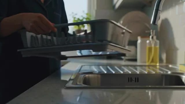 Person Placing Dish Rack on Modern Kitchen Counter