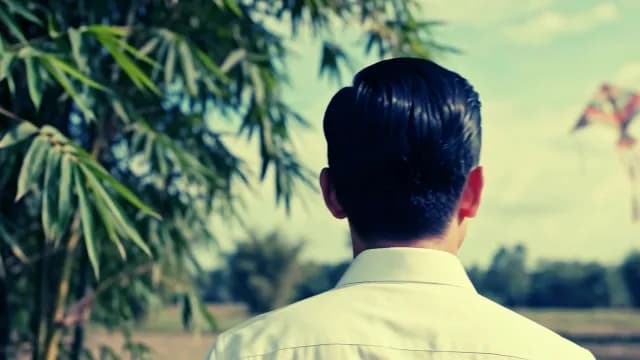 Man in White Shirt Watching Kite Over Rural Field
