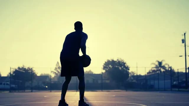 Silhouette of Basketball Player Training on Outdoor Court at Sunrise