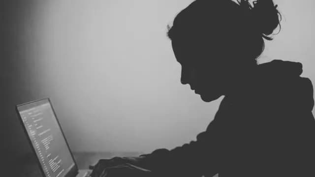 Silhouette of Female Developer Coding on Laptop in Dark Room
