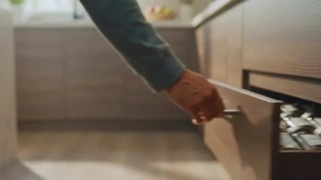 Person Opening Wooden Kitchen Drawer Filled with Spice Jars