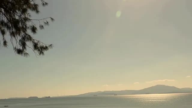 Golden Hour Coastal Landscape with Calm Sea and Distant Mountains