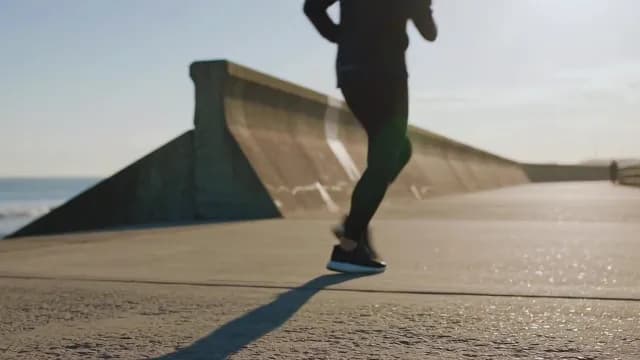 Silhouette Jogging Along Coastal Sea Wall at Sunrise