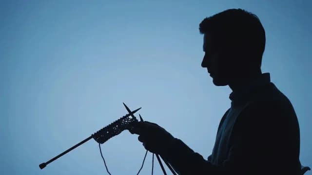 Silhouette of Man Knitting Against Blue Background