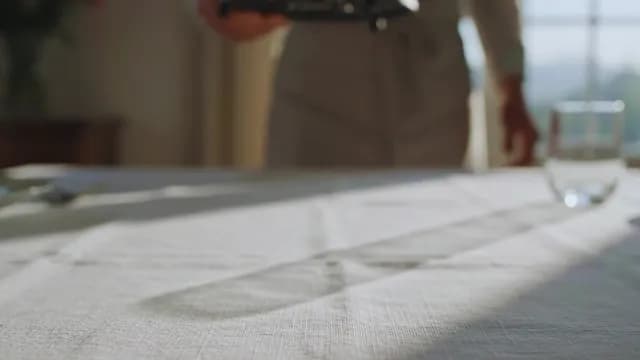 Waiter setting a white linen table in natural sunlight