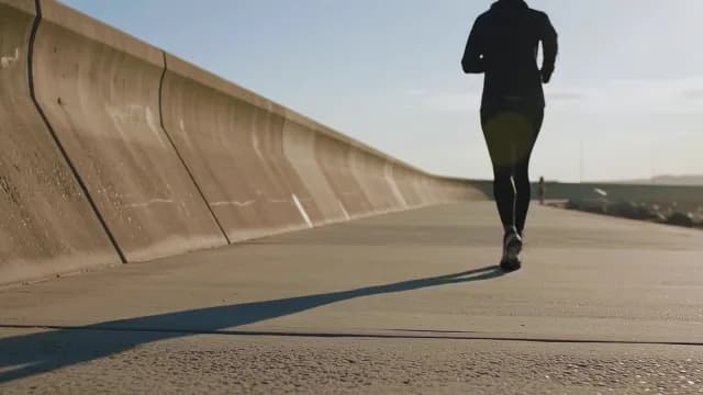 Silhouette of Runner Jogging on Coastal Promenade at Sunrise