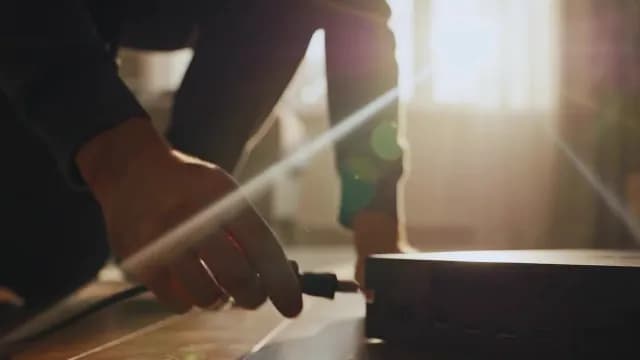 Close Up Hand Plugging Cable into Tech Device with Sunflare