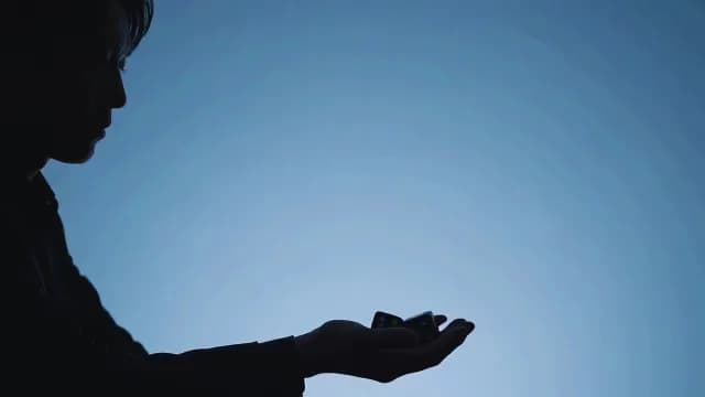 Silhouette of Person Holding Dice Against Blue Background