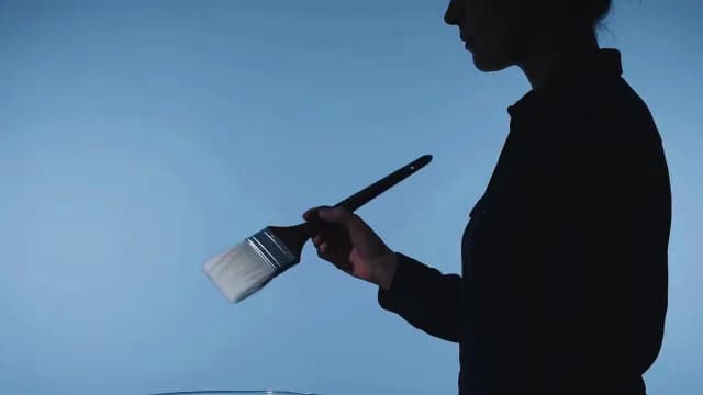 Silhouette of Artist with Paintbrush on Blue Studio Background