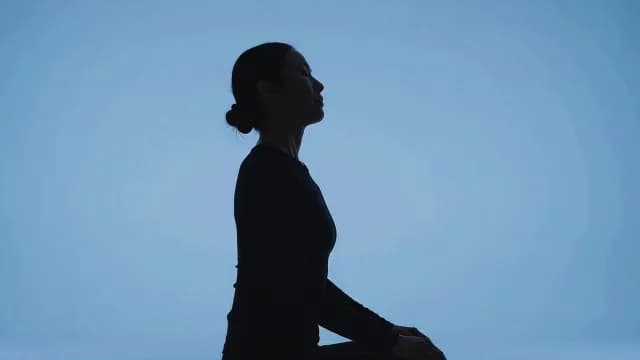 Silhouette of Woman Meditating in Blue Studio Setting
