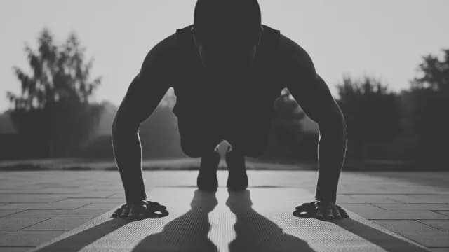 Black and White Silhouette of Man Doing Outdoor Pushups