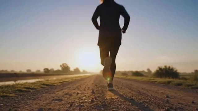 Athletic Woman Jogging on Dirt Road at Sunrise Silhouette