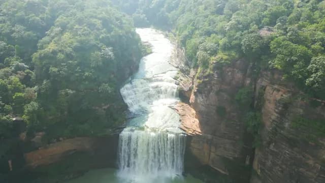 Aerial Shot of Majestic Tiered Waterfall in Lush Green Canyon of Rajdari Devdari Dam