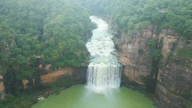 Aerial View of Majestic Tiered Waterfall in Lush Green Canyon of Rajdari Devdari Dam