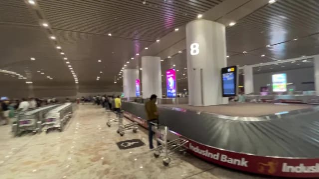 Passengers Waiting at Airport Baggage Claim Carousel in Mumbai