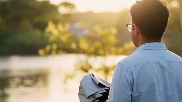 Man Watching Sunset Over Calm Lake During Golden Hour
