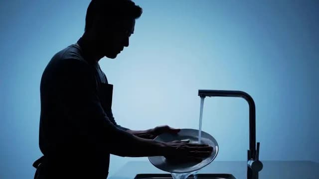 Silhouette of Man Washing Dishes in Blue Studio Lighting