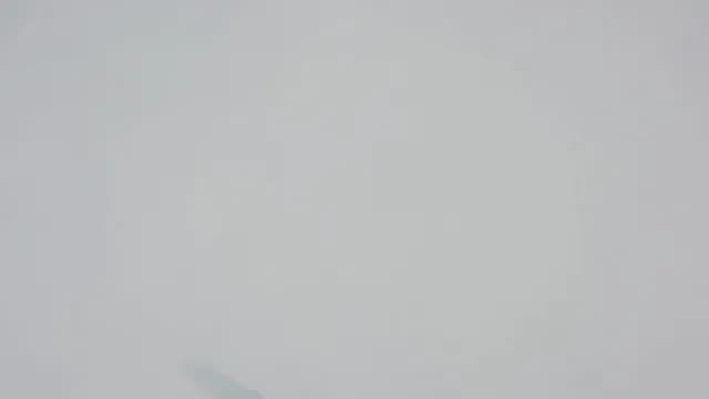 Aerial view of a lone man walking through deep fresh powder snow creating a trail