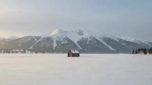 Isolated Wooden Cabin in Snow-Capped Mountain Landscape