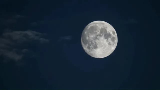 Glowing Full Moon in Clear Night Sky with Faint Clouds