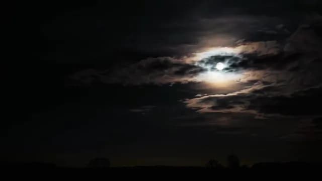 Full Moon Shining Through Dark Clouds at Night