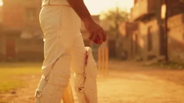 Cricket Player Walking Across Dusty Field at Golden Hour