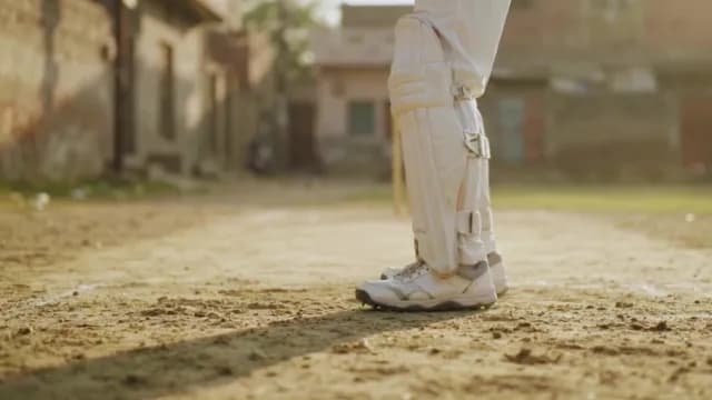Cricket Player in Protective Gear on Village Field