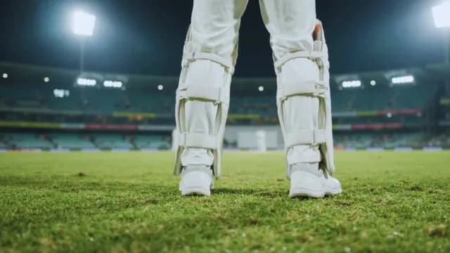 Professional Cricket Batsman Standing on Pitch in Night Stadium