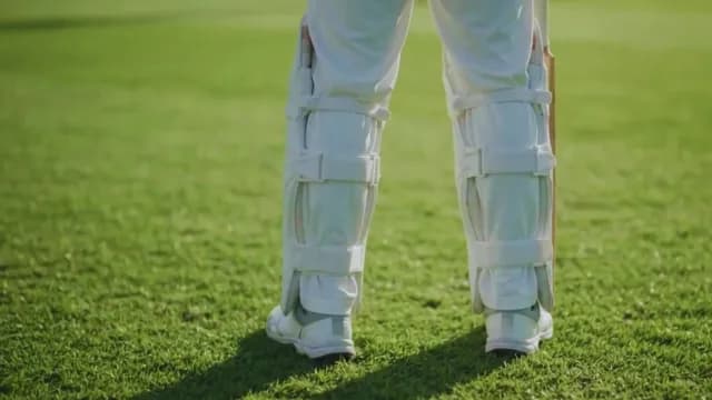 Rear View of Cricket Player in White Protective Gear on Pitch
