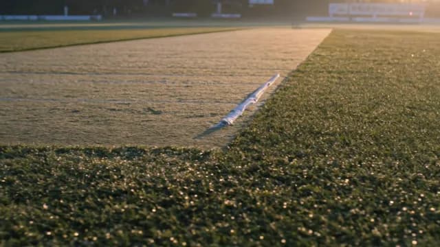 Sunlit Cricket Pitch with Morning Dew at Dawn