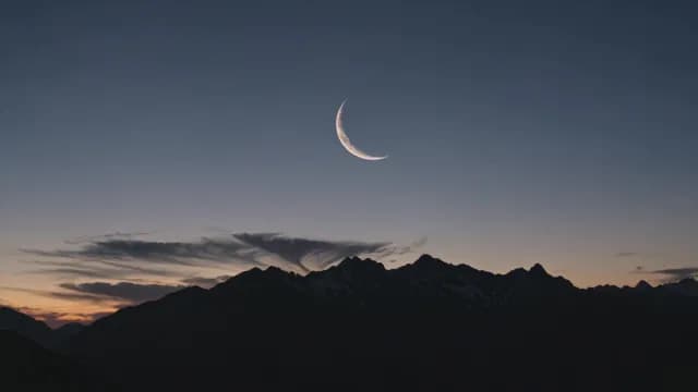 Crescent Moon over Silhouetted Mountain Range at Twilight
